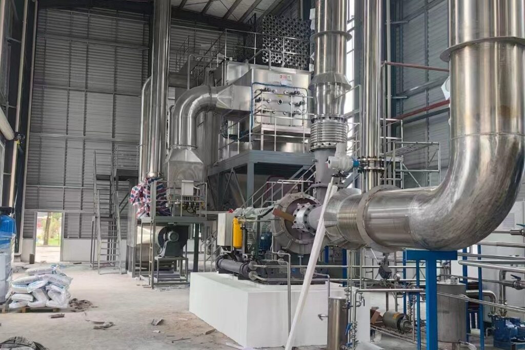 Large diameter stainless steel pipework and elbows of a process line inside the workshop